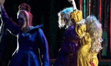 a woman in a blue dress and a woman in a yellow dress are dancing together