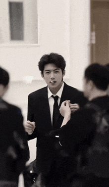 a man in a suit and tie is standing in a room with other people