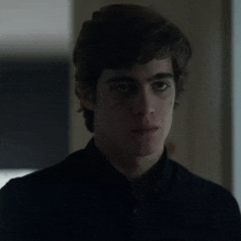 a close up of a young man in a black shirt looking at the camera .