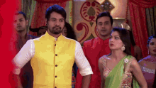 a man in a yellow vest is standing next to a woman in a green sari