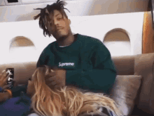a man wearing a green supreme sweatshirt holds a woman 's hair