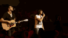 a man singing into a microphone while another man plays guitar