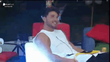 a man is sitting on a couch with a microphone in his mouth .