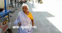 an elderly woman is walking down a street in front of a cart and talking in a foreign language .