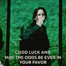 a picture of a woman covering her mouth with her hand with the words good luck and may the odds be ever in your favor .
