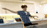 a man in a plaid shirt is standing in a kitchen
