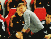 a group of soccer players are sitting in a stadium and one of them is wearing an adidas jersey