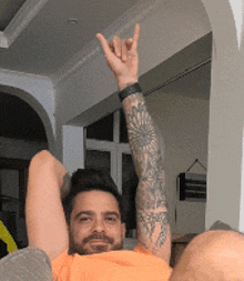a man with a tattoo on his arm is laying on a couch with his arm in the air
