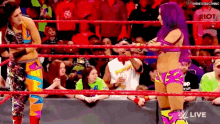 two women are wrestling in a ring with a crowd watching .