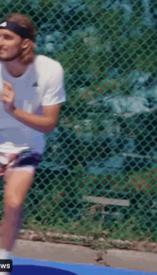 a man wearing a headband and a white shirt is playing tennis