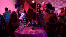 a group of people are gathered around a table with small rainbow flags on it