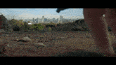 a person walking on a rocky hillside with a city skyline in the background