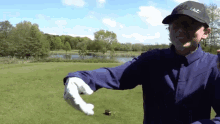 a man wearing a black titleist hat holds a golf ball