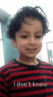 a young boy wearing a red and black striped shirt says i don 't know .