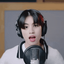 a young man wearing headphones singing into a microphone with a aa gif on the bottom right