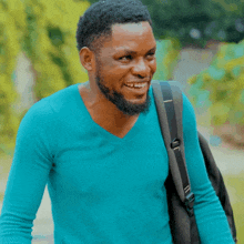 a man in a blue shirt is carrying a black backpack