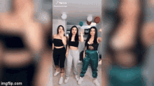 three women are dancing together in a room with balloons .