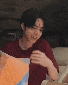 a young man in a red shirt is holding a colorful pillow .