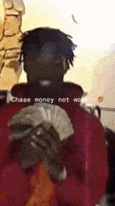 a man in a red jacket is holding a bunch of money with the words " chase money not women " above him