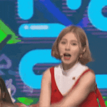 a woman in a red dress and white collar is singing into a microphone on stage .