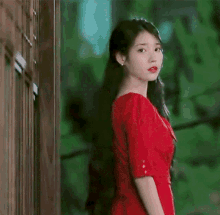 a woman in a red dress is standing in front of a building .