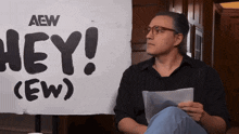 a man is sitting in front of a sign that says hey