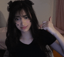 a girl with black stars on her face is giving a thumbs up