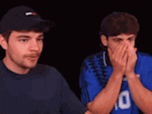 two men are covering their faces with their hands and one of them has the number 10 on his jersey