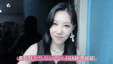 a woman wearing a necklace with a cross on it and earrings says " i 'm sorry "