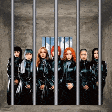 a group of women standing behind bars in a jail cell