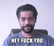 a man with a beard is sitting in a chair and saying hey fuck you