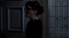 a woman wearing glasses is screaming in front of a blue door