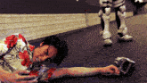 a man in a floral shirt is laying on the ground with a robot in the background