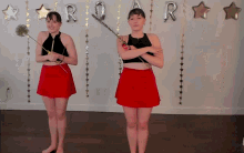 two women in red skirts are standing in front of balloons that spell out roar
