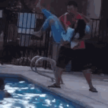 a man is carrying a woman over a pool