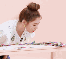 a woman in a bun is blowing confetti on a table