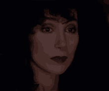 a close up of a woman 's face in the dark with a serious look on her face .