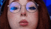 a close up of a woman 's face wearing glasses and a nose ring .