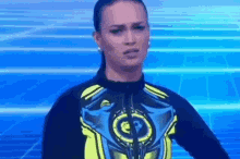 a woman in a blue and yellow outfit is standing in front of a blue background on a television screen .