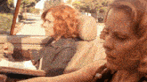 two women are sitting in a car looking out the window and one of them is wearing a denim jacket