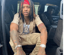 a man with dreadlocks wearing a bandana and a necklace with the number 0 on it