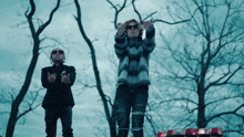two men standing next to each other with their hands up
