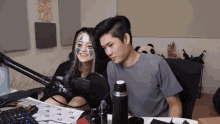 a man and a woman are sitting in front of a microphone with a panda in the background