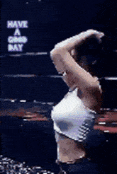 a woman in a white tank top is standing in front of a sign that says have a good day .
