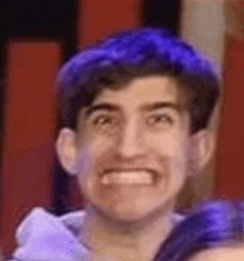 a man with blue hair is making a funny face .