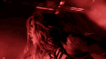 a woman is dancing in a dark room with red light behind her
