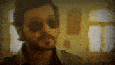 a man with a beard is wearing sunglasses and a trench coat