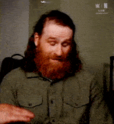 a man with a beard is sitting in front of a sign that says w / n live kansas city