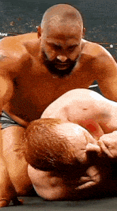a man with a beard is wrestling another man in a wrestling match