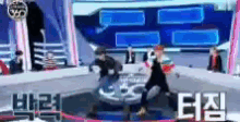 a group of people are dancing on a stage in front of a large screen with chinese writing on it